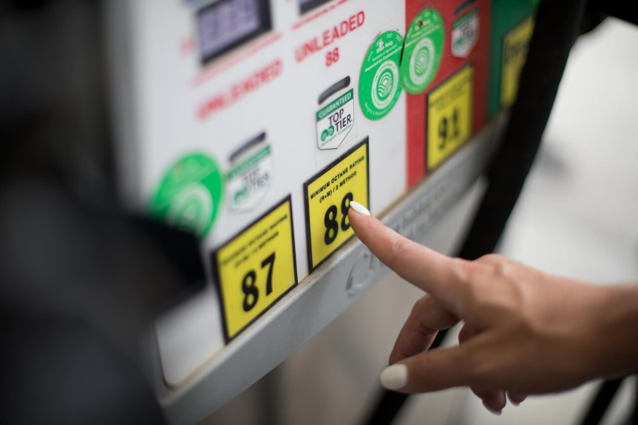 Photo of a person's hand pointing at Unleaded 88 at a fuel pump